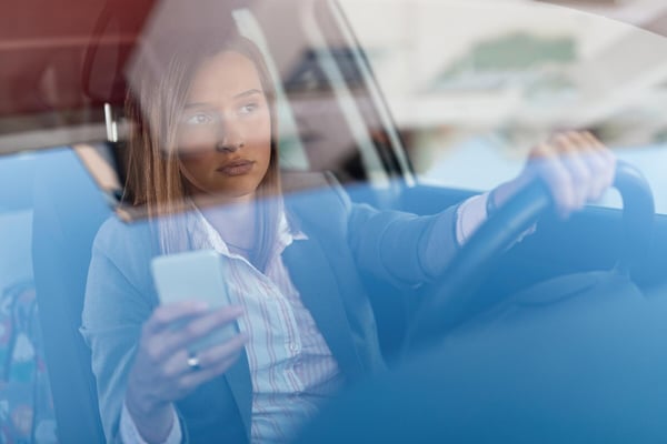 beautiful-businesswoman-driving-work-using-cell-phone-wheel-view-is-through-glass_637285-2090
